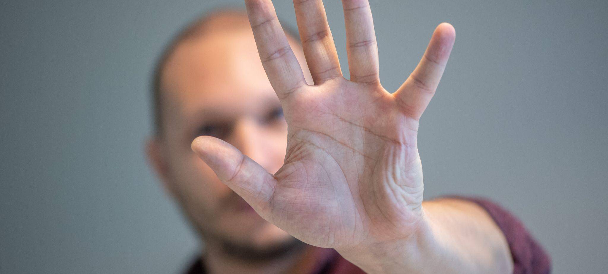 Ein Mann hebt schützend die Hand vor sein Gesicht