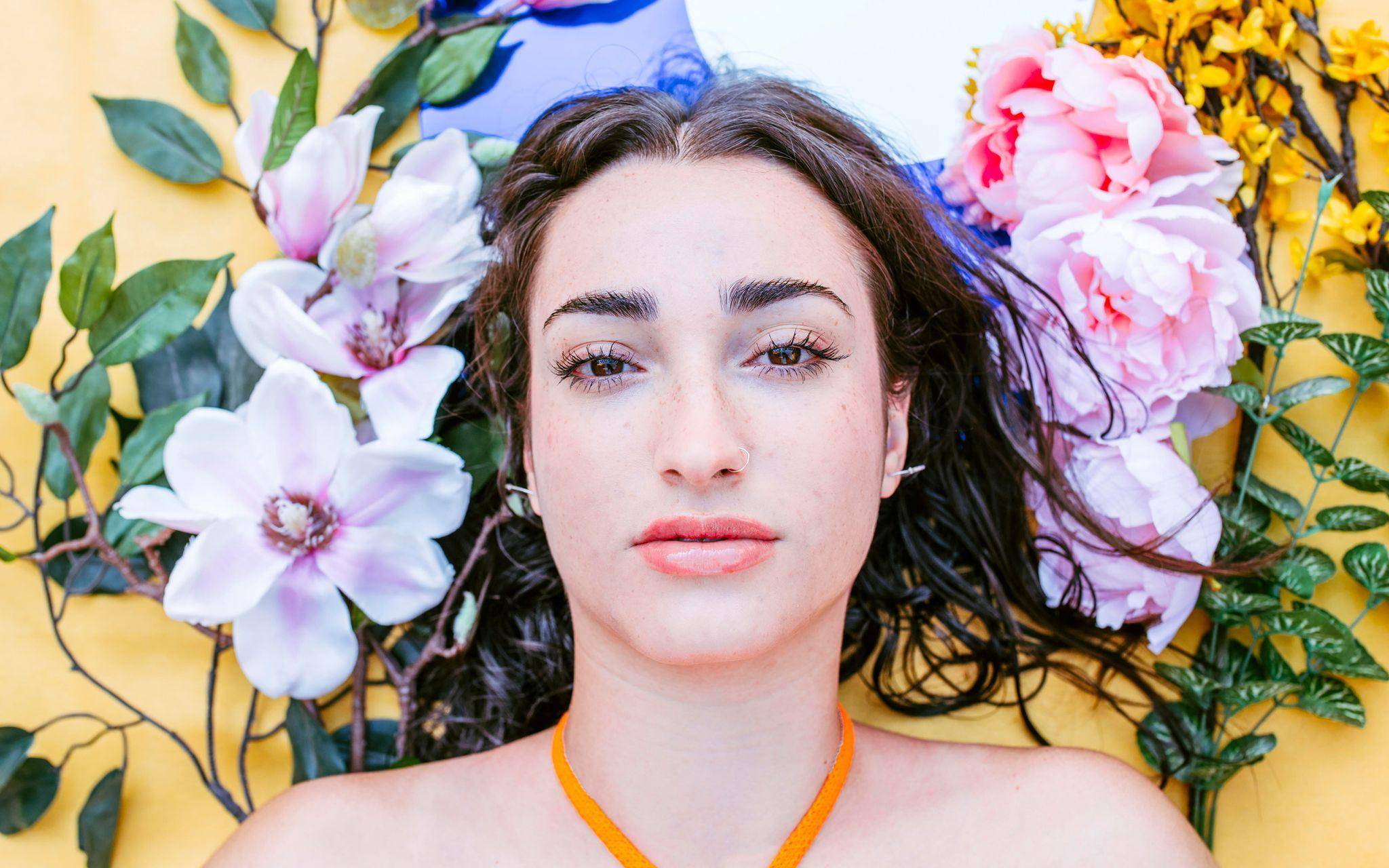 Natürlich geschminkte Frau liegt neben Blumen