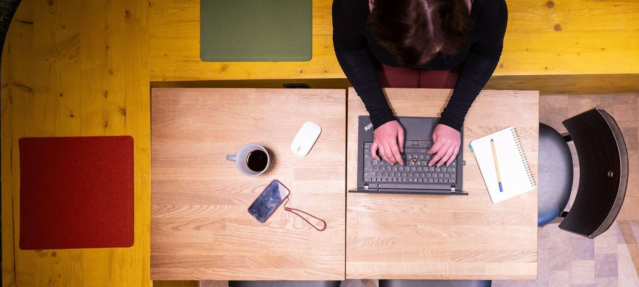 Frau sitzt im Homeoffice am Küchentisch und arbeitet am Laptop