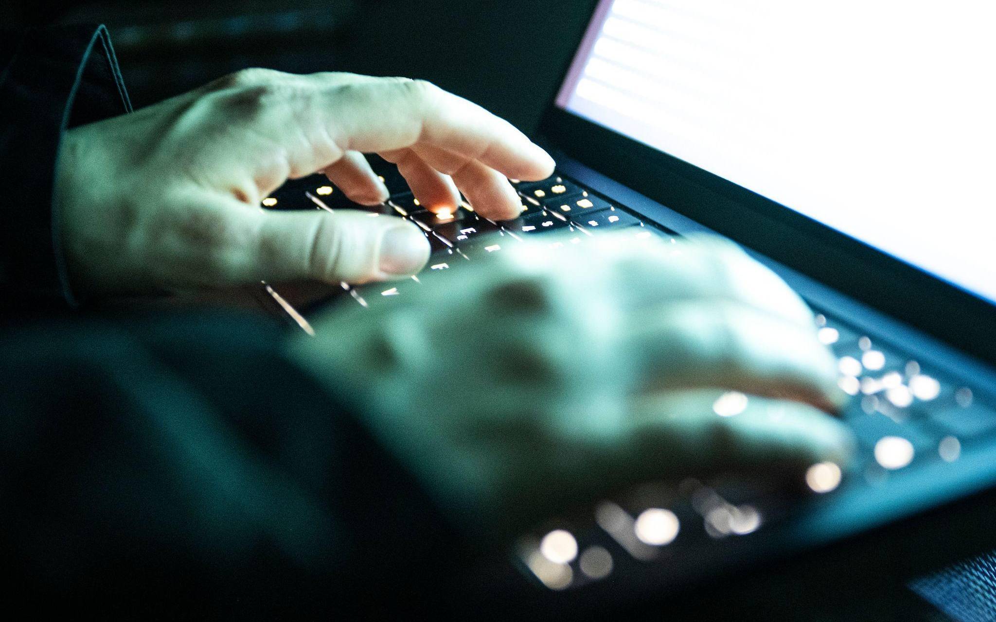 Eine Person tippt auf einer beleuchteten Laptop-Tastatur