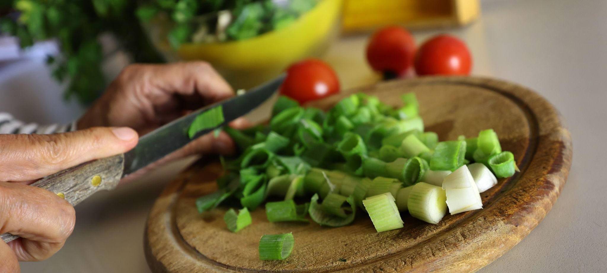 Eine Frau schneidet beim Kochen Lauchzwiebeln