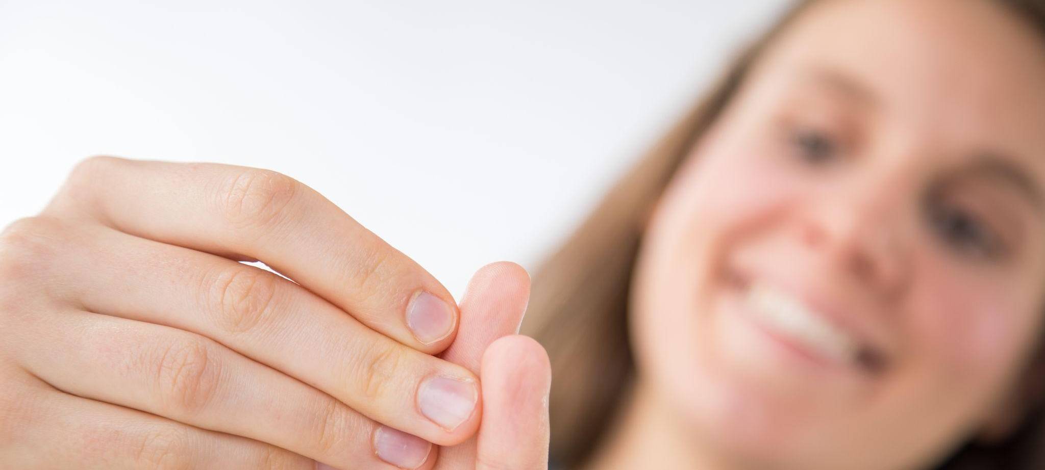 Eine Frau betrachtet ihre Fingernägel