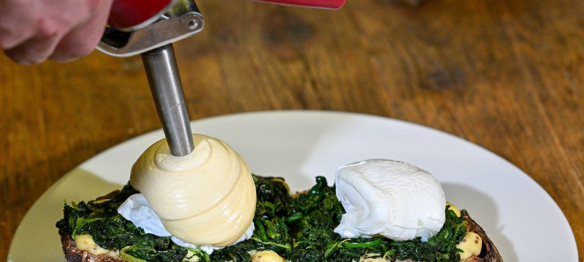 Koch richtet Sauce Hollandaise mit einem Sahnesyphon an