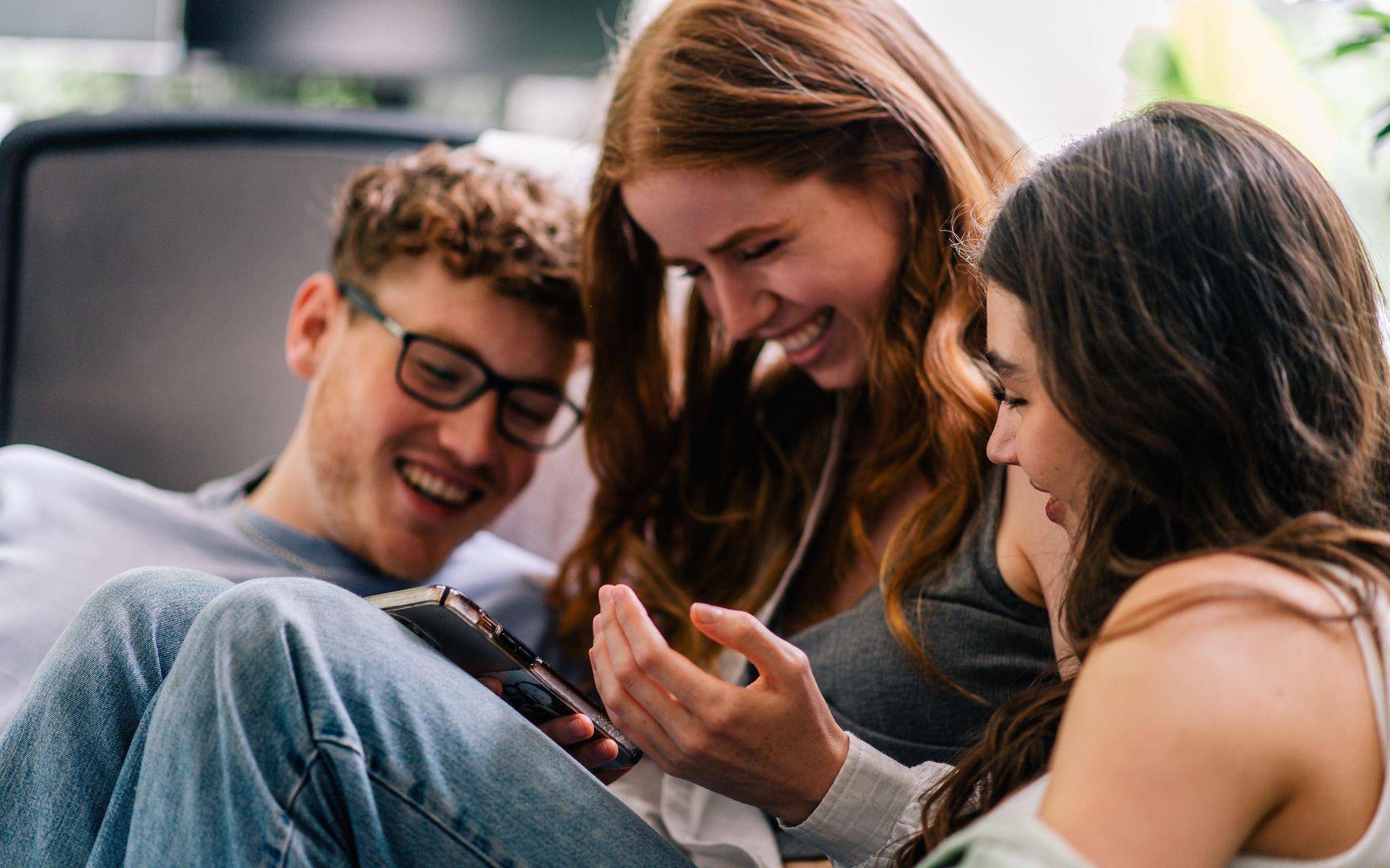 Drei Freunde schauen gemeinsam aufs Handy