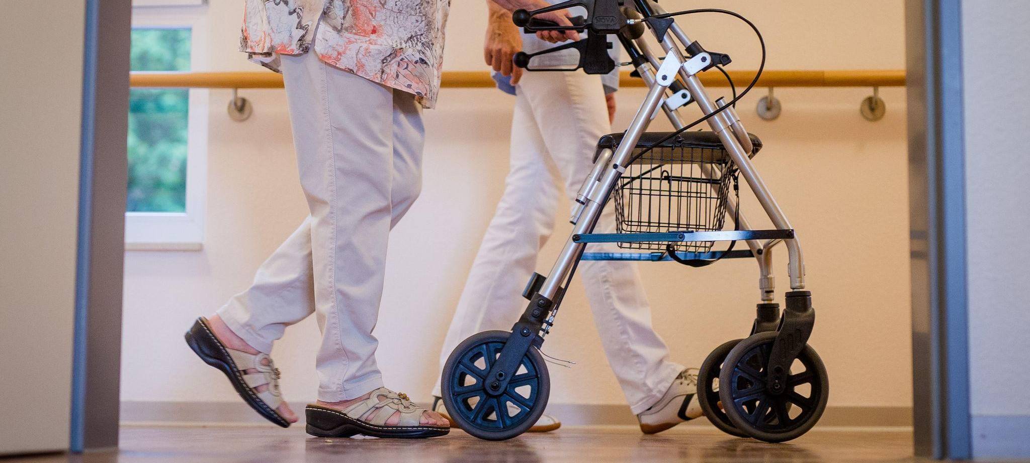 Pflegekraft mit einer älteren Dame in einem Pflegeheim