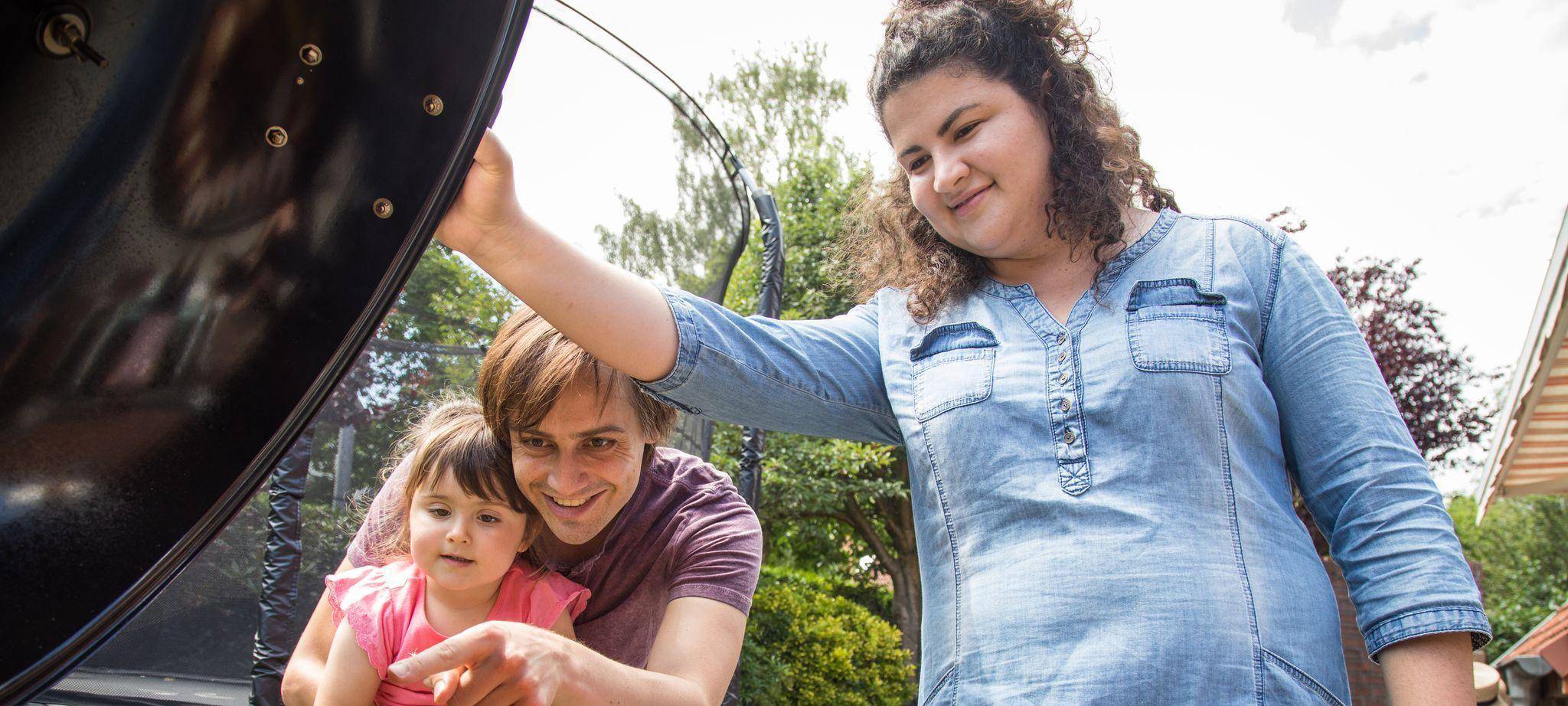 Eltern stehen mit ihrer Tochter vor einem Grill