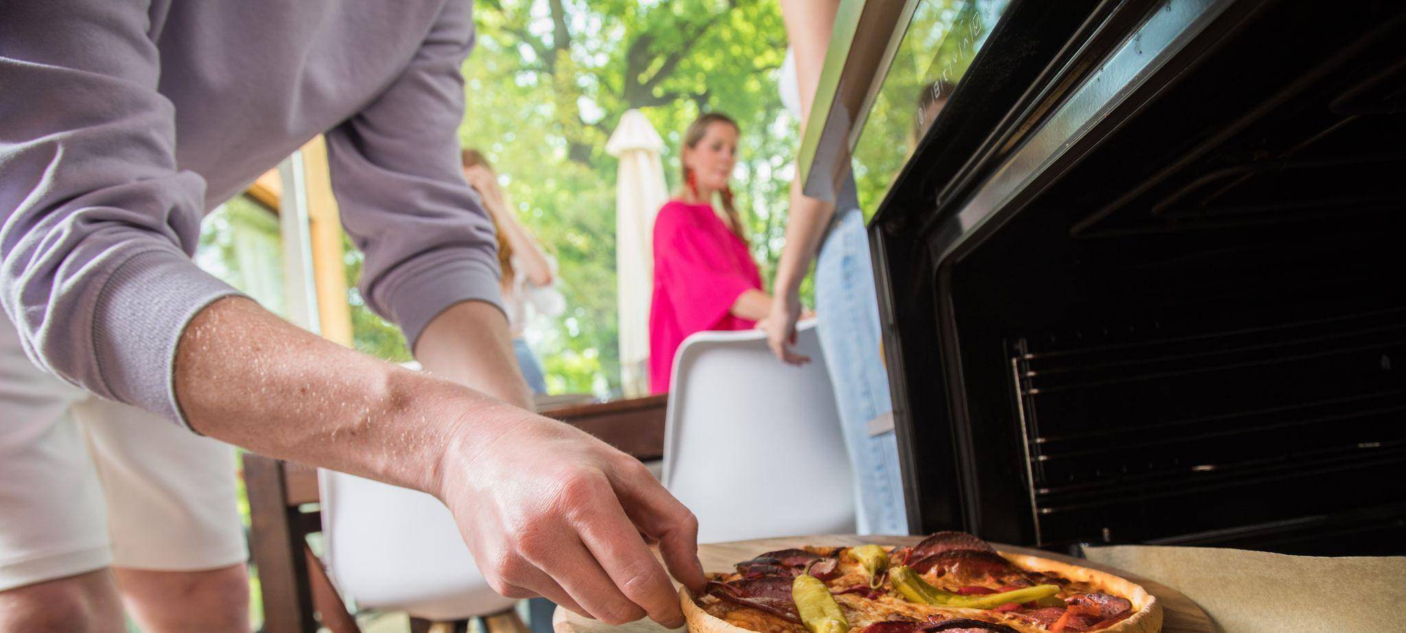 Ein Mann holt eine Pizza aus dem Ofen