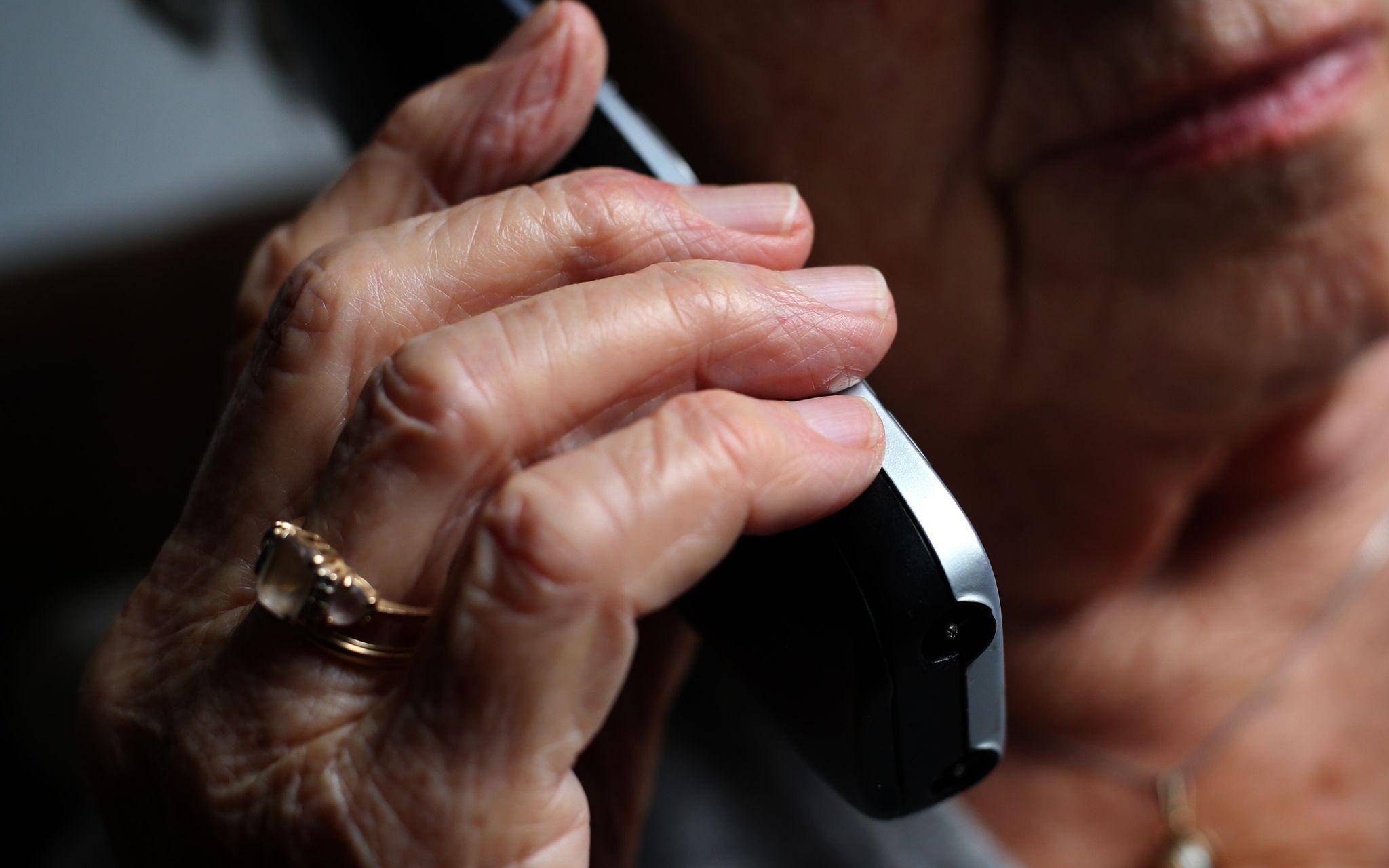 Seniorin telefoniert mit einem Festnetztelefon